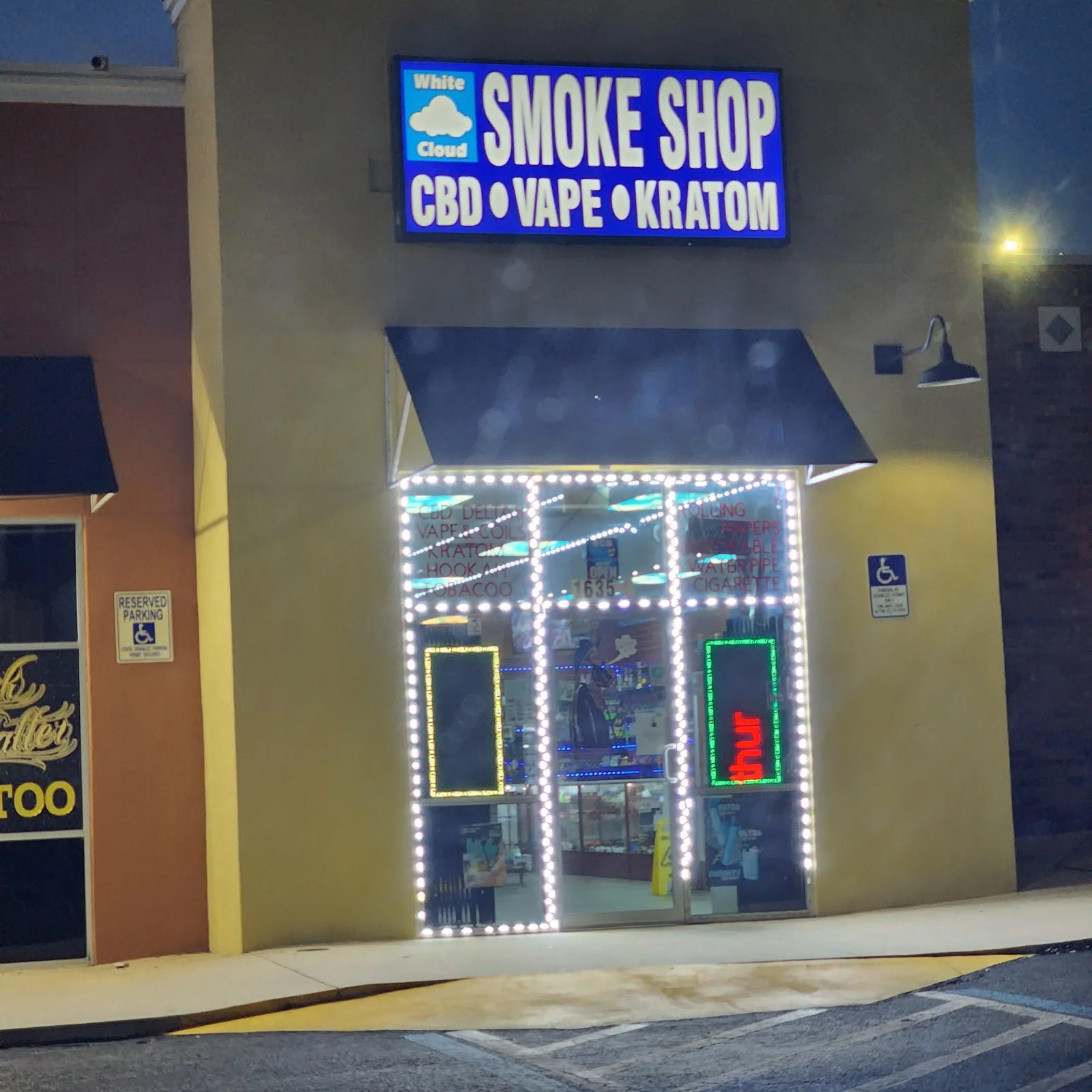 White Cloud Smoke Shop storefront lit up at night, sign reading Smoke Shop, CBD, Vape, Kratom